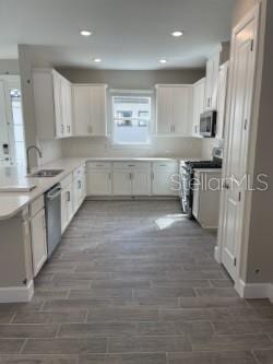 kitchen with dark wood-type flooring, sink, white cabinetry, and appliances with stainless steel finishes