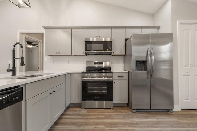 kitchen featuring stainless steel appliances, sink, lofted ceiling, ceiling fan, and gray cabinetry