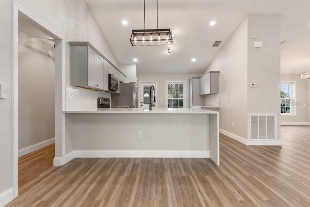 kitchen with vaulted ceiling, gray cabinetry, and appliances with stainless steel finishes