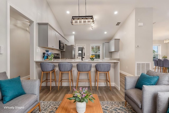 kitchen with gray cabinetry, a kitchen breakfast bar, vaulted ceiling, and kitchen peninsula