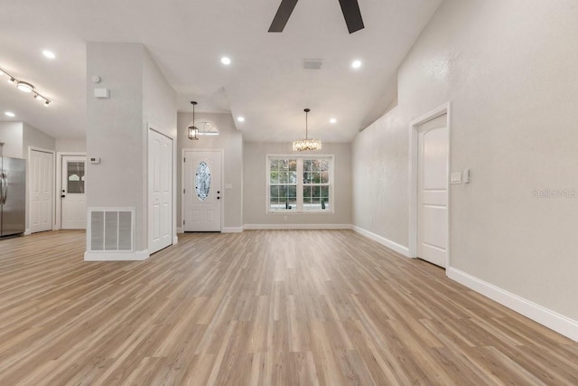 unfurnished living room featuring light wood-type flooring, high vaulted ceiling, and ceiling fan with notable chandelier