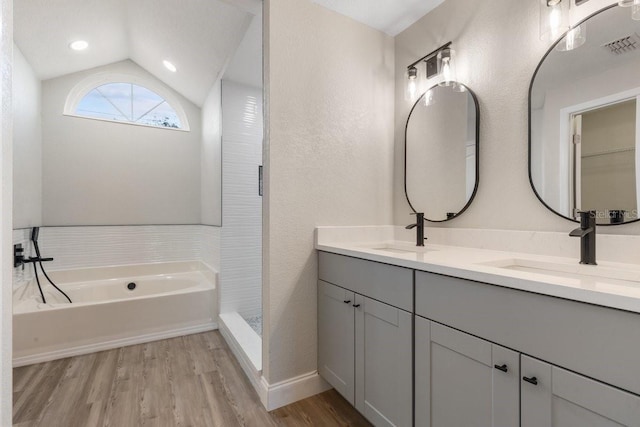 bathroom featuring hardwood / wood-style floors, lofted ceiling, vanity, and shower with separate bathtub