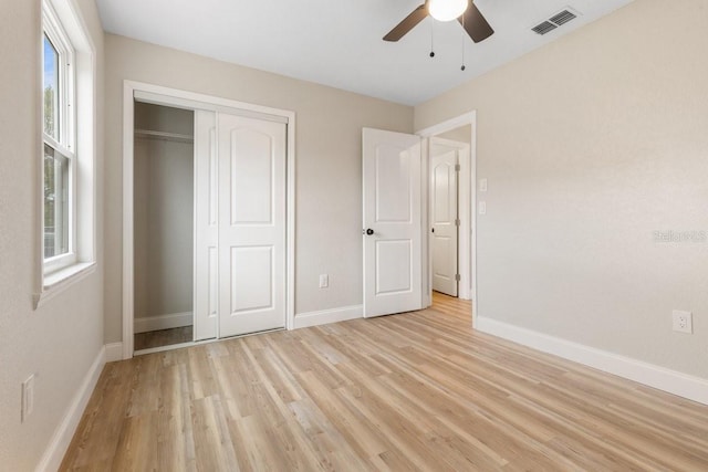 unfurnished bedroom with ceiling fan, light wood-type flooring, and a closet