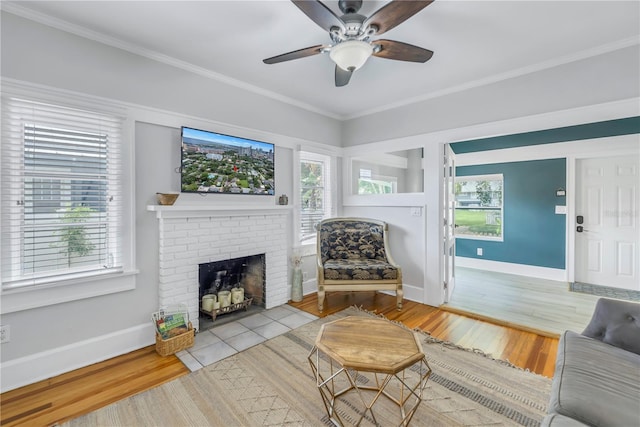 living room featuring crown molding, light hardwood / wood-style flooring, a brick fireplace, and a wealth of natural light