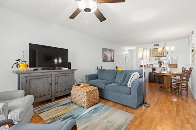 living room featuring a textured ceiling, ceiling fan with notable chandelier, and light hardwood / wood-style flooring