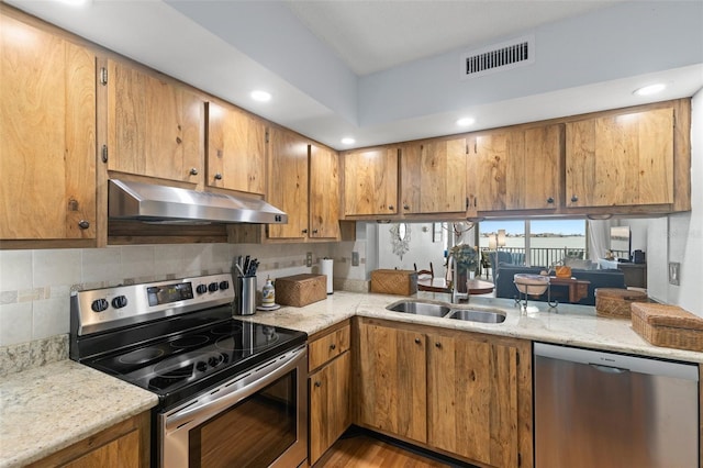 kitchen with light stone counters, sink, backsplash, and stainless steel appliances