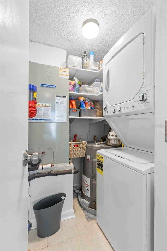 laundry room featuring stacked washer and dryer, light tile patterned floors, and a textured ceiling