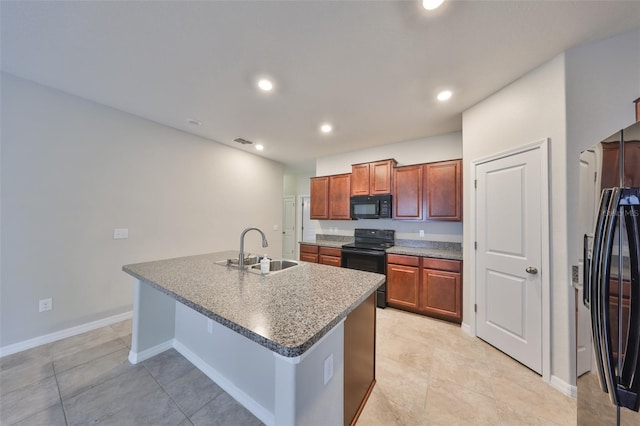 kitchen featuring sink, black appliances, a kitchen island with sink, and a breakfast bar