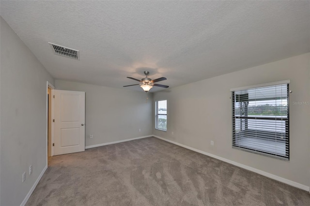 unfurnished room with ceiling fan, light colored carpet, and a textured ceiling