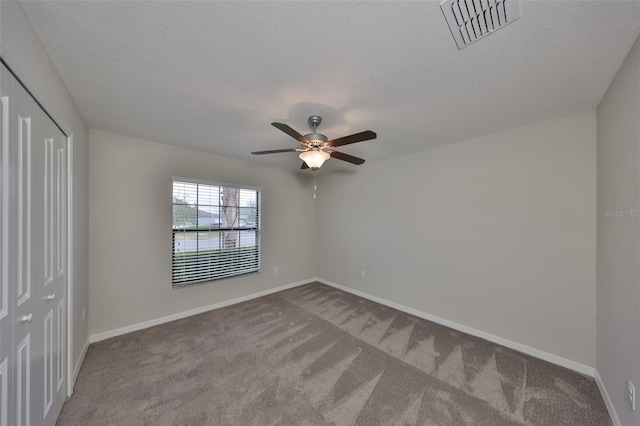 unfurnished bedroom with a closet, ceiling fan, carpet flooring, and a textured ceiling