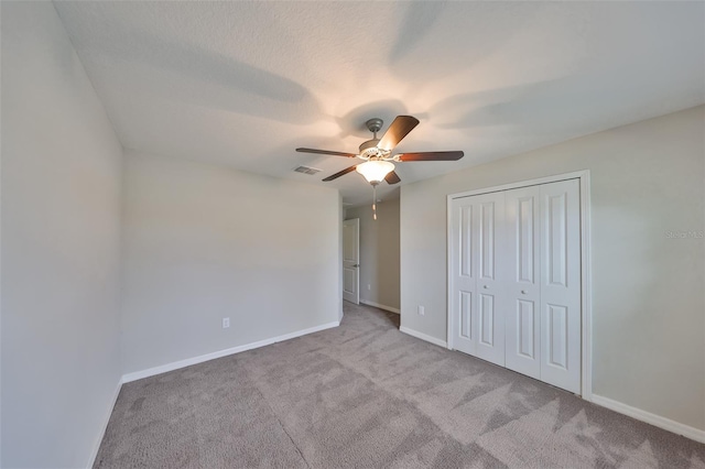 unfurnished bedroom featuring a closet, ceiling fan, a textured ceiling, and light carpet