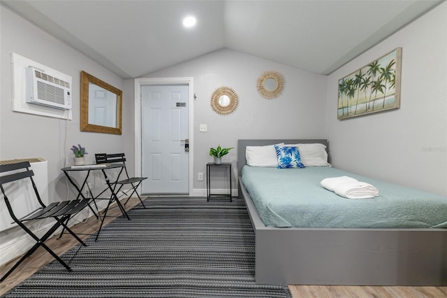 bedroom with vaulted ceiling, dark hardwood / wood-style floors, and a wall mounted AC