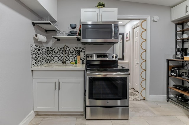 kitchen with white cabinetry, lofted ceiling, sink, light tile patterned floors, and stainless steel appliances