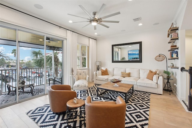 living room with light wood-type flooring, ceiling fan, and a water view