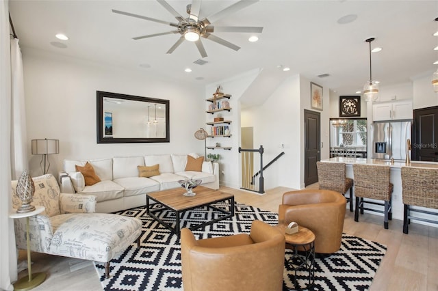 living room with light hardwood / wood-style floors, ornamental molding, and ceiling fan