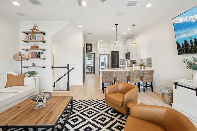 living room with crown molding and light hardwood / wood-style flooring