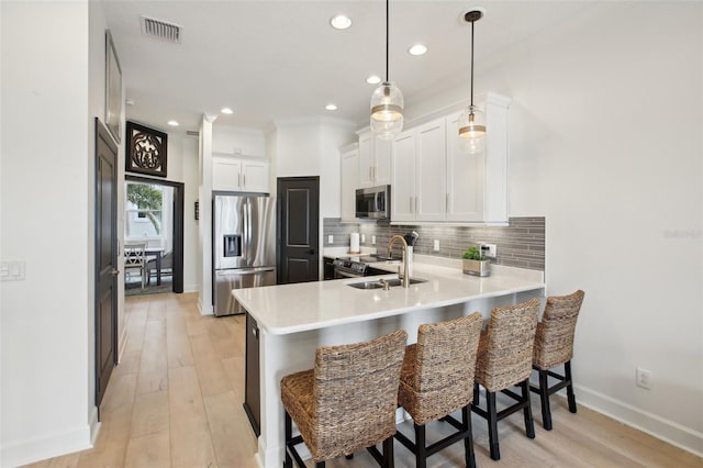 kitchen with a kitchen bar, sink, white cabinetry, and appliances with stainless steel finishes