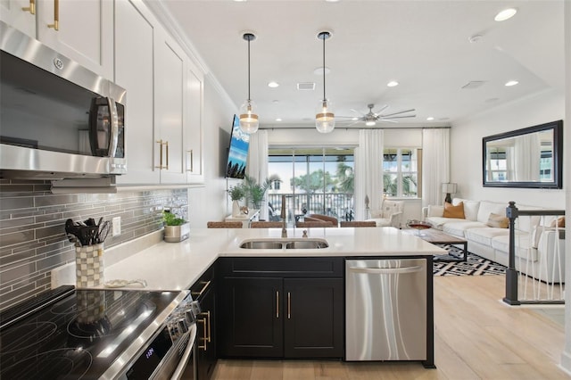 kitchen with decorative light fixtures, sink, light hardwood / wood-style flooring, stainless steel appliances, and white cabinets