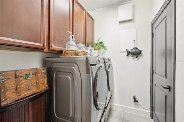 laundry area featuring light tile patterned floors, washing machine and clothes dryer, and cabinets