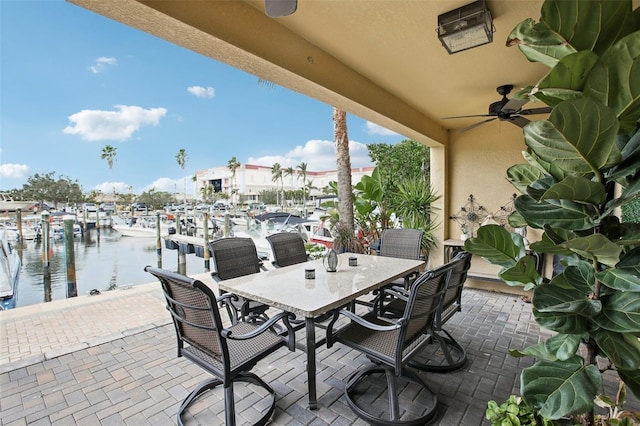 view of patio featuring ceiling fan, a dock, and a water view