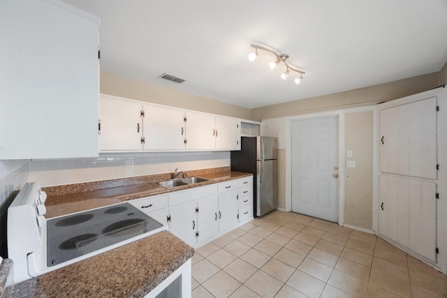 kitchen with white cabinets, range, sink, stainless steel fridge, and light tile patterned flooring