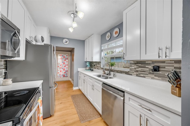 kitchen with sink, white cabinets, light hardwood / wood-style floors, and appliances with stainless steel finishes