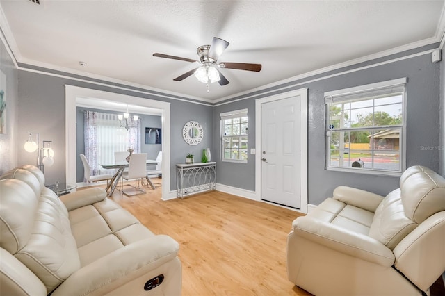 living room with ceiling fan with notable chandelier, plenty of natural light, hardwood / wood-style flooring, and crown molding