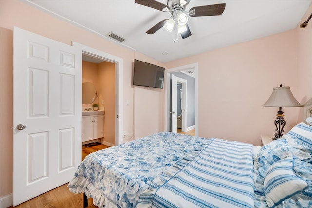 bedroom with ensuite bathroom, light wood-type flooring, and ceiling fan