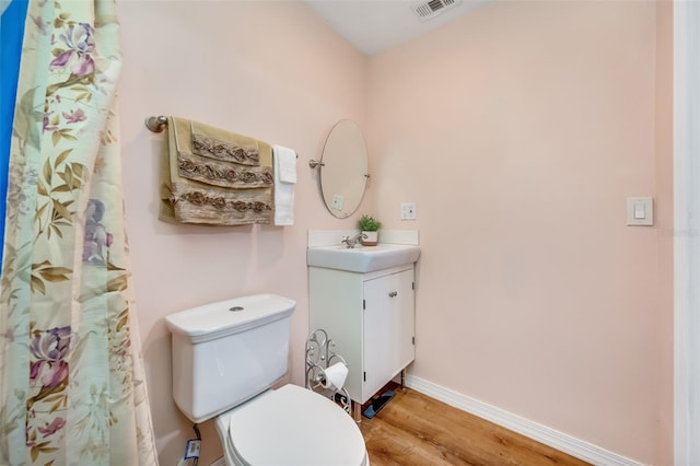 bathroom with toilet, hardwood / wood-style flooring, and vanity