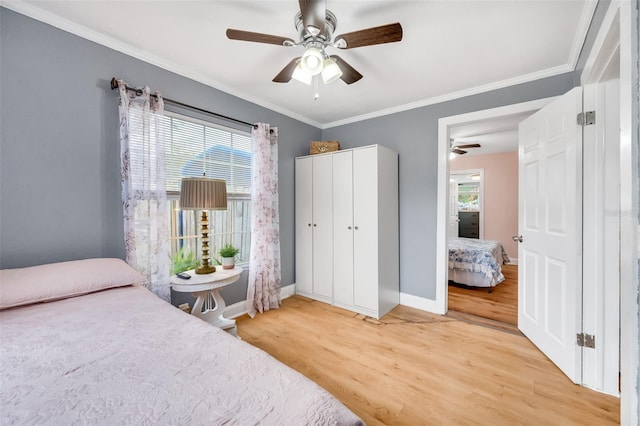 bedroom featuring ornamental molding, light wood-type flooring, ceiling fan, and multiple windows