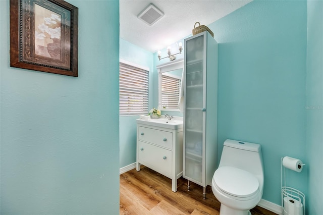 bathroom featuring toilet, wood-type flooring, vanity, and a textured ceiling