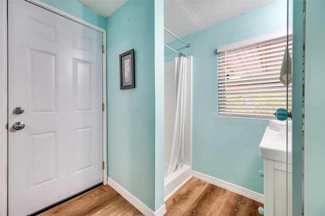 bathroom featuring a shower with shower curtain, a textured ceiling, and hardwood / wood-style floors