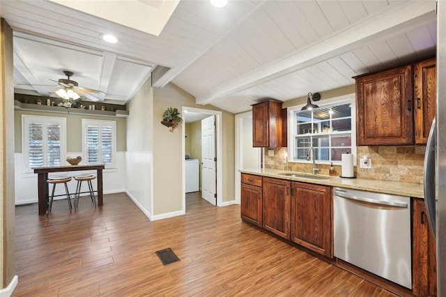 kitchen featuring tasteful backsplash, dishwasher, lofted ceiling with beams, sink, and light stone countertops