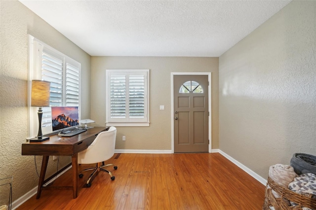 office space with a textured ceiling, a wealth of natural light, and hardwood / wood-style floors