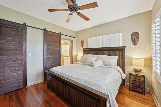 bedroom with ceiling fan, a barn door, and hardwood / wood-style floors