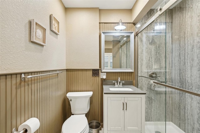 bathroom featuring a shower with door, toilet, and vanity