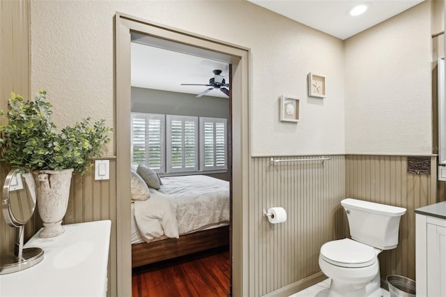 bathroom with toilet, vanity, ceiling fan, and wood-type flooring