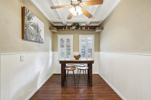 dining area with coffered ceiling, ceiling fan, dark wood-type flooring, ornamental molding, and beamed ceiling