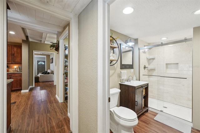 bathroom with toilet, a shower with door, wood-type flooring, vanity, and beamed ceiling