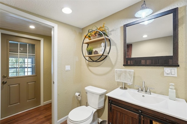 bathroom with toilet, vanity, and wood-type flooring