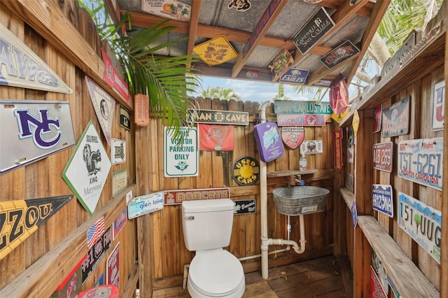 bathroom with toilet and wooden walls