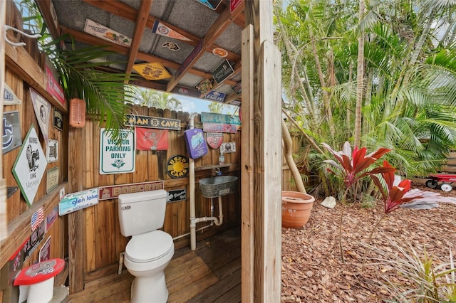 bathroom featuring toilet and wood walls