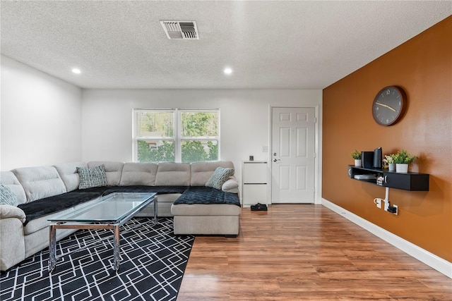 living room featuring wood-type flooring and a textured ceiling