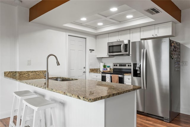 kitchen with hardwood / wood-style floors, white cabinetry, stainless steel appliances, sink, and kitchen peninsula