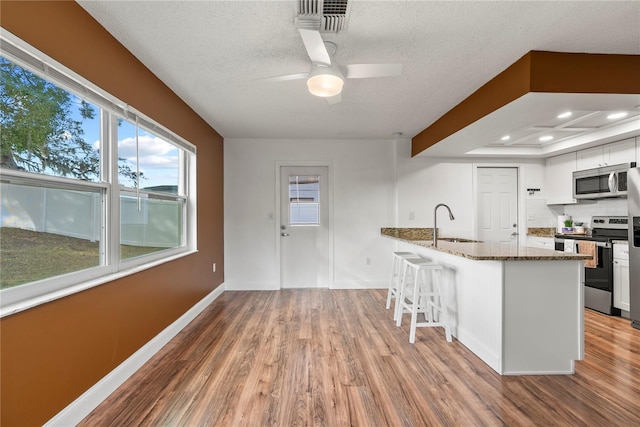 kitchen featuring white cabinets, appliances with stainless steel finishes, dark stone counters, sink, and backsplash