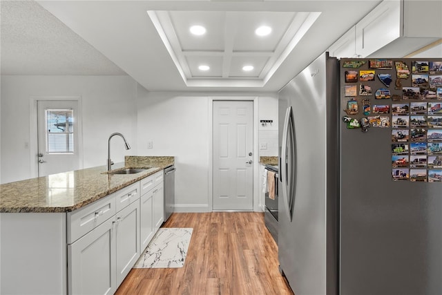 kitchen with light hardwood / wood-style floors, appliances with stainless steel finishes, sink, dark stone countertops, and white cabinets