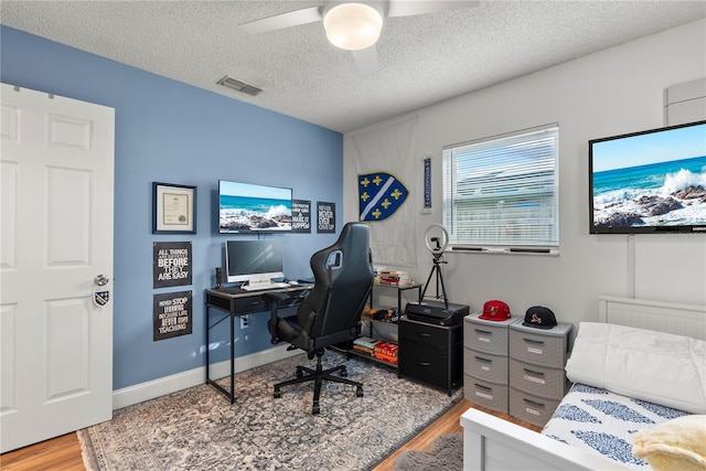 office space featuring hardwood / wood-style flooring, ceiling fan, and a textured ceiling