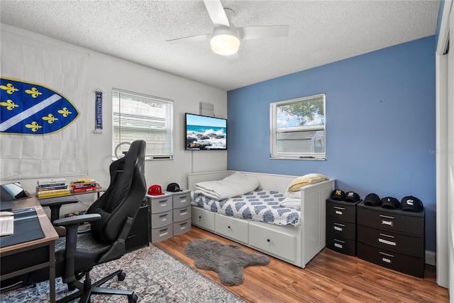 bedroom featuring ceiling fan, multiple windows, and a textured ceiling