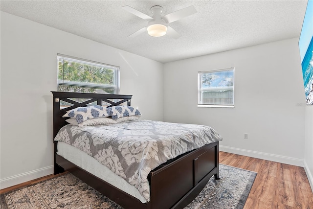 bedroom with hardwood / wood-style floors, a textured ceiling, and ceiling fan