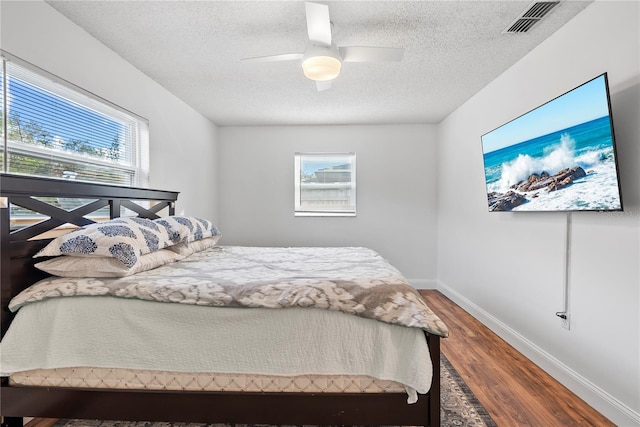 bedroom featuring ceiling fan, a textured ceiling, and dark hardwood / wood-style flooring